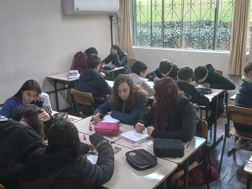 Alunos concentrados escrevendo em seus cadernos durante a atividade